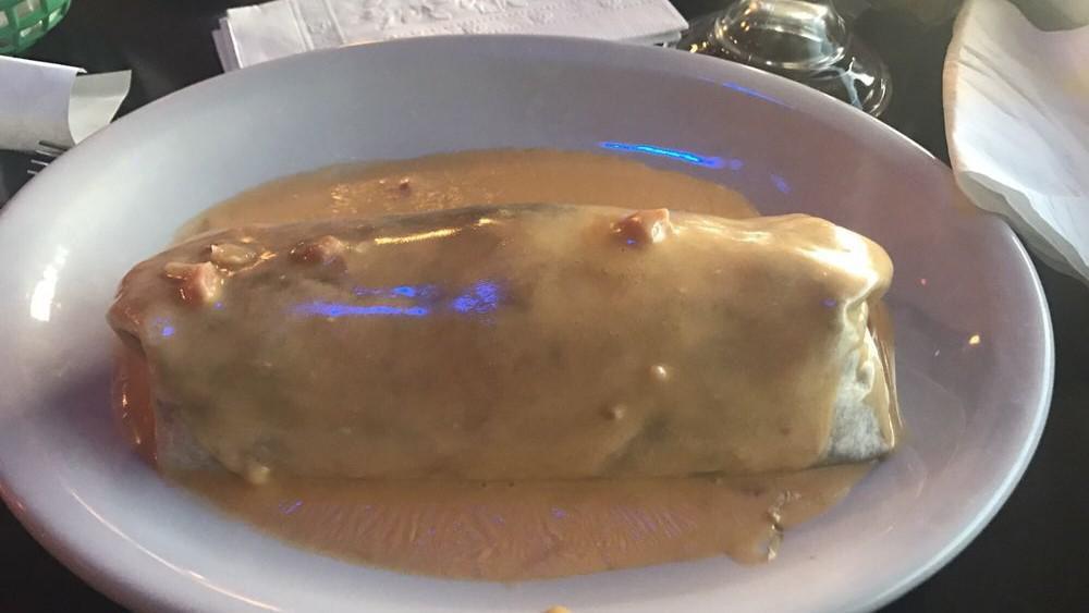 Jerry'S Burrito · A large flour tortilla wrap filled with shredded or ground beef, refried beans, rice, cheese, and topped with chile con queso. Served with lettuce and tomatoes on the side.