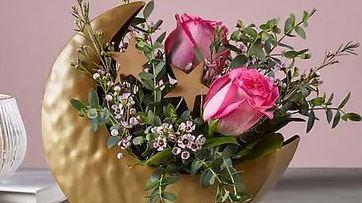 Over The Moon Bouquet · This stunning celestial bouquet is out of this world, featuring a keepsake crescent moon vessel filled with  lush pink roses and seasonal filler & greens.  The arrangement stands approximately 10