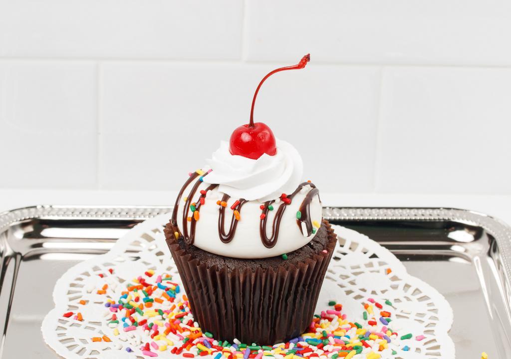 Sundae Cupcake · Our moist chocolate cake filled with fudge topped with vanilla buttercream, a fudge drizzle, peanuts, a dollop of whip, and a cherry.