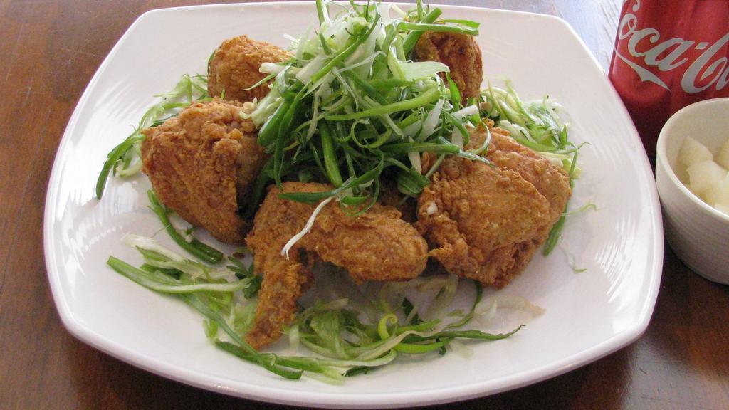 Padak · Fried chicken  (drum, stick, thigh, wing, a breast) with raw green onions.
Drumstick, thigh, one side of breast in half and a wing.