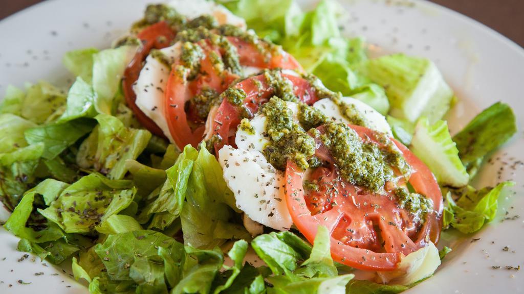 Caprese Salad · Slices of buffalo mozzarella and sliced tomatoes, drizzled with extra virgin olive oil, balsamic vinegar, pesto and herbs on a bed of lettuce.