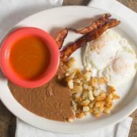 Huevos Rancheros · two eggs over easy served with tomato sauce bacon strips and tortillas.