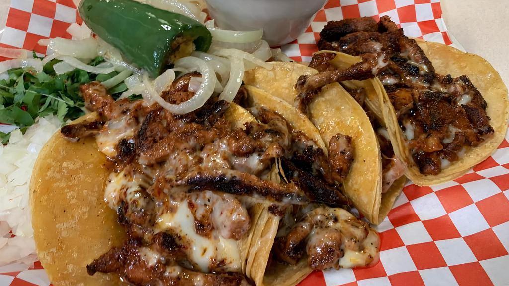 Gringitas · Four pastor mini tacos on homemade corn tortillas with melted Monterrey cheese, served with onions, cilantro, grilled onions, limes, fried jalapeño pepper and borracho beans,.