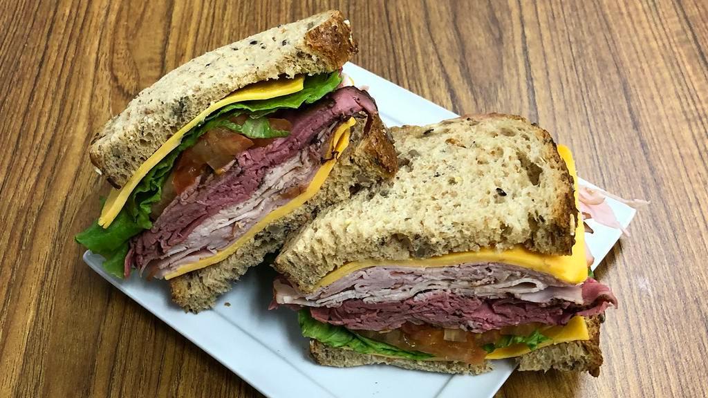 The Stacker · Honey ham, roast beef, oven roasted turkey, mild cheddar cheese, with lettuce, tomato, red onion, and sliced dill pickle on multi-grain bread.