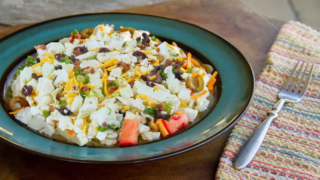 Bacon Ranch Cauliflower Salad · Crunchy cauliflower, diced roma tomatoes, shredded cheddar cheese, green onions, green olives, and bacon bits all tossed with buttermilk ranch dressing.