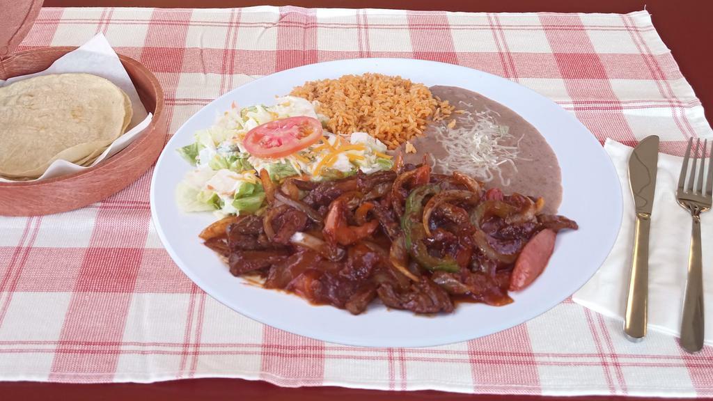 Steak Ranchero · Beef cooking in a mild sauce. Included onions, bell peppers, tomato, rice, beans, salad & choice of flour or handmade corn tortillas.