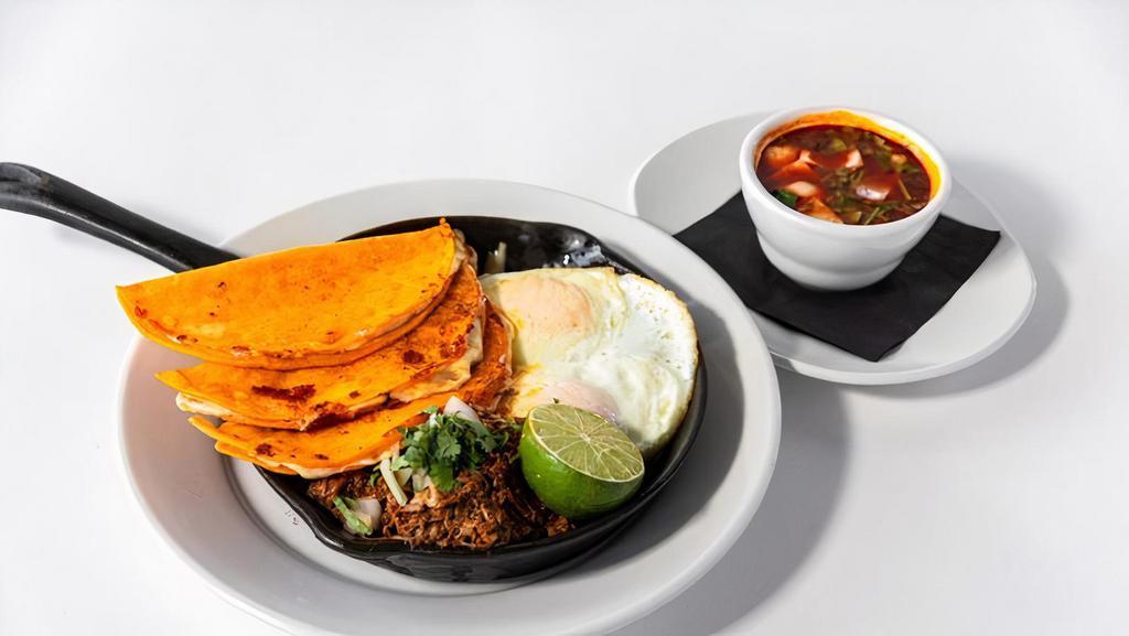 The Best F#*%Ing Birria Hash · Slow chili braised beef / hash potatoes / mozzarella cheese / taco shells / diced white onions / cilantro / fried egg / consommé