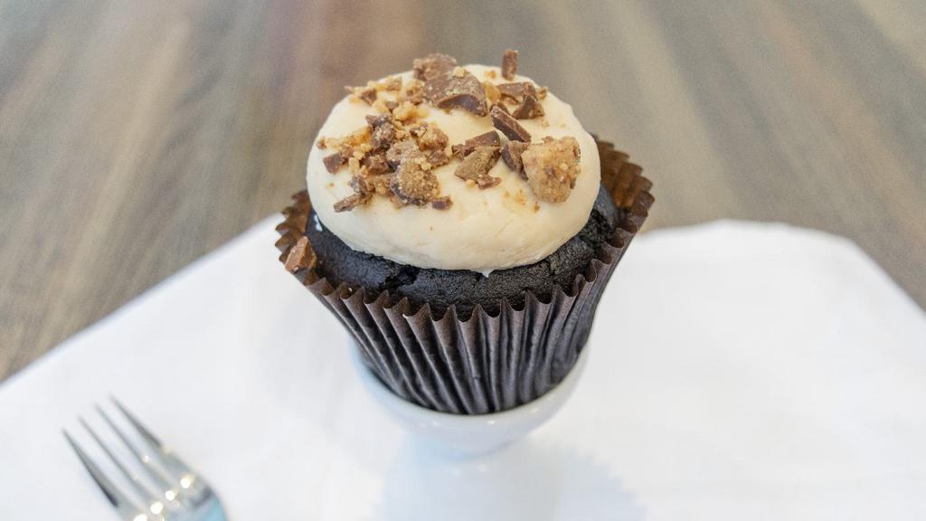 Peanut Butter Cup Cupcake · Chocolate cake with peanut butter cream cheese frosting topped with crumbled peanut butter cups.
