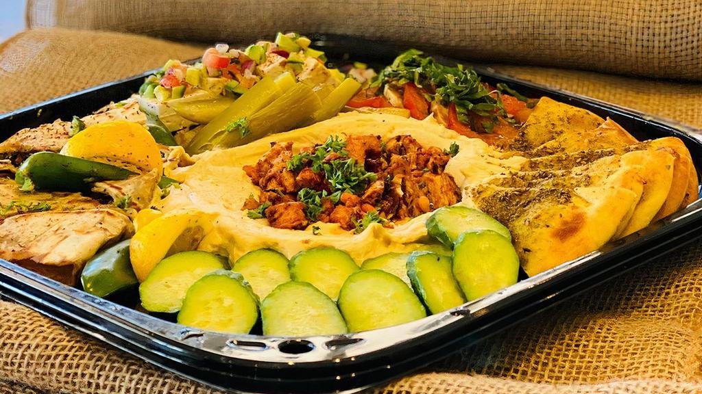 Mezze Platter · Happy Hour Tapas assortment: hummus & chicken with pine nuts, fresh mozzarella & tomato, baked pita chips, kafta mini pockets, feta, pickles, cucumbers