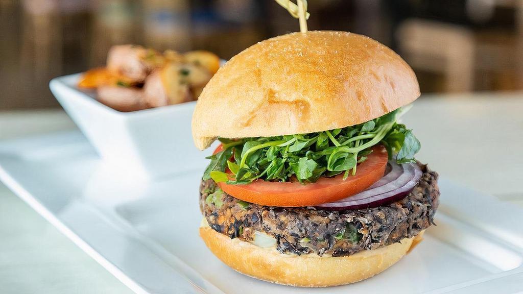 Chipotle Black Bean Burger · homemade black bean patty formed with chipotle, jalapenos and bell peppers, carrots, corn, oats, garlic, onion, fresh cilantro, cranberries, chipotle hummus, baby arugula, hothouse tomato, sliced red onions, spinach, bun