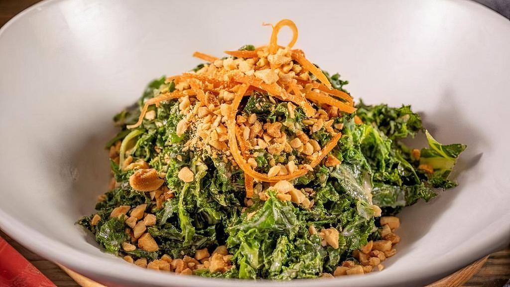 Kale Salad In Sesame Dressing · Blanched Kale tossed with sesame dressing, topped off with shredded carrots and a sprinkle of crushed peanuts.