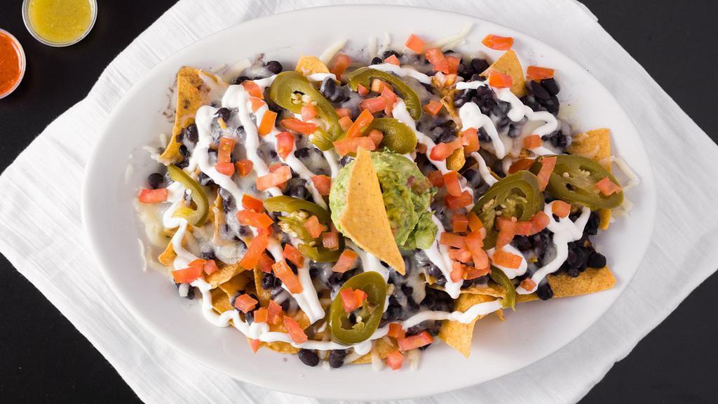 Nachos · Served with tortilla chips, cheese, black beans, sour cream, guacamole, tomatoes, and pickled jalapeños.