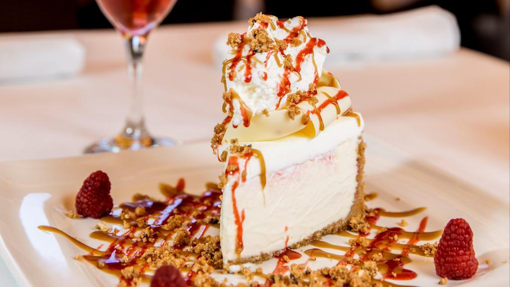 White Chocolate Raspberry Cheesecake · A creamy, soft raspberry infused cheesecake. Topped with fresh raspberries, whipped cream, and caramel sauce.
