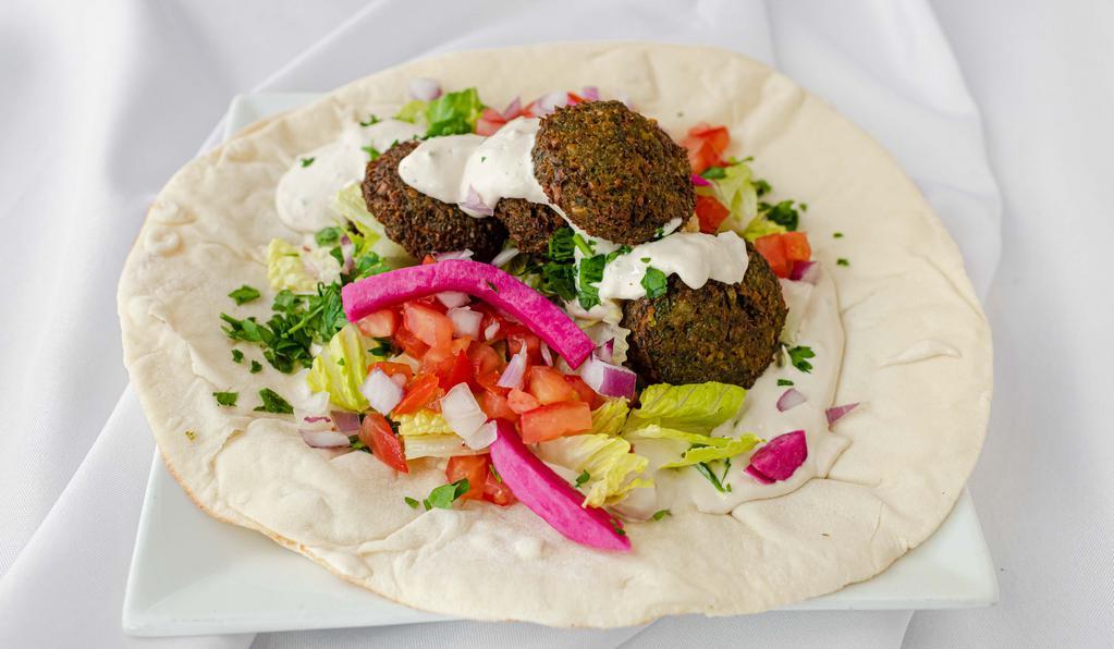 Falafel Wrap · Garbanzo beans, parsley, onion, and spices formed into balls and fried. Made with tahini. Each wrap is loaded with lettuce, onions, tomatoes, pickled turnips, and parsley. VGN