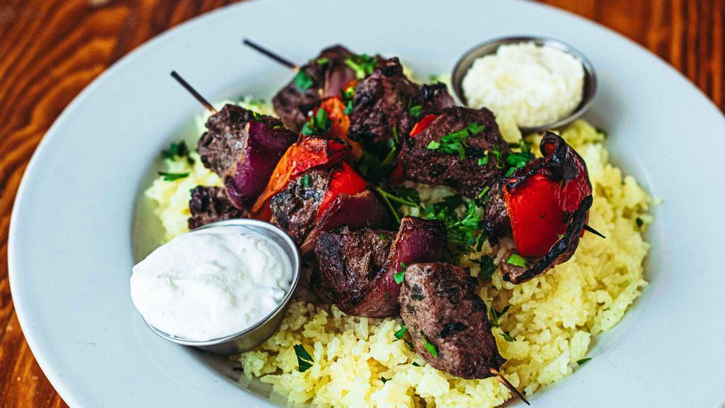 Lamb Kabobs Plate · Lamb marinated in olive oil, garlic, mint, and lemon. Kabob plates are served with two skewers over saffron jasmine rice. Served with tzatziki and toum. GF