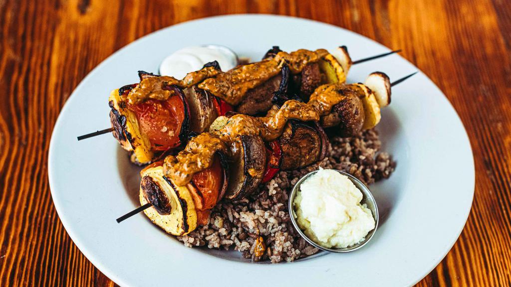 Veggie Kabobs Plate · Tomato, potato, eggplant, mushroom, zucchini, and garlic topped with our sweet pesto herb dressing, and served over majadra. Served with tahini and toum. GF VGN