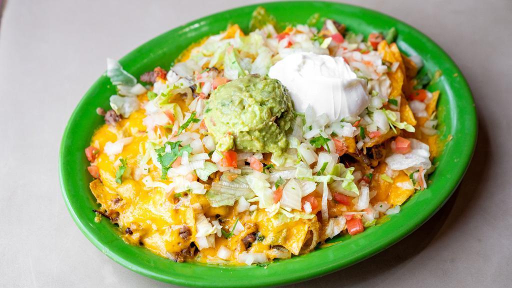 Nachos Fajita · Choice of meat, chicken or steak or shredded pork, served with beans, tomatoes, cilantro, onions, bell peppers, lettuce, cheddar cheese, guacamole and sour cream.