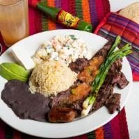 Churrasco Chapin · Grilled steak marinated to perfection, served with green onions, rice, refried black beans a...