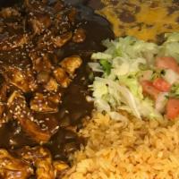 Pollo En Mole · Chicken served in a tasty, sweet, and spicy Mexican sauce with tortillas, rice and beans.