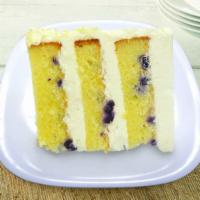 Colossal Lemon Blueberry Cake Slice · 3 layers of Lemon Blueberry Crème Cake frosted & filled with Lemon Buttercream garnished wit...