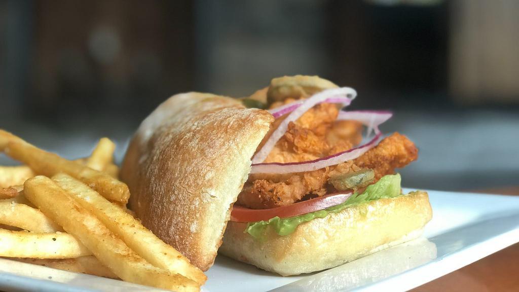 Cajun Chicken Sandwich · Fried cajun chicken breast with roma crunch lettuce, shaved red onion and sliced tomatoes topped with fried jalapeño medallions. Served on a toasted ciabatta bun with avocado spread and chipotle aioli.