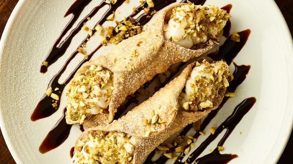 Traditional Cannoli** · Two crisp pastry shells stuffed with sweet ricotta and chocolate chip filling, topped with pistachios and powdered sugar