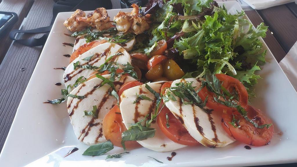 Caprese Salad · Sliced tomatoes, sliced buffalo mozzarella, spring mix tossed in oil and vinegar and fresh basil with a balsamic drizzle.