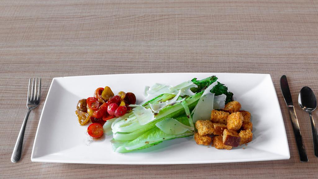 Grilled Romaine Caesar Salad · Chopped grilled romaine heart, house Caesar dressing, shaved parmesan, heirloom cherry tomatoes and our house made sourdough croutons.