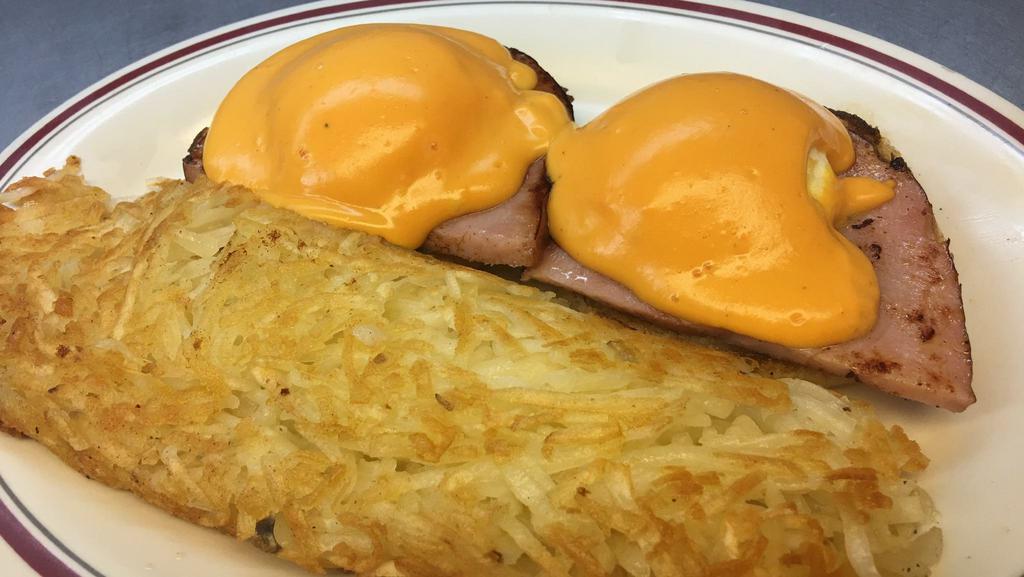 Eggs Benedict · Two eggs and ham served on an English muffin and smothered with cheese sauce. Served with hash browns.