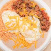 Steak Ranchero Breakfast Plate · Two sunny side-up eggs with steak, pico de gallo, and enchilada sauce on a plate with rice a...