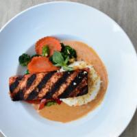 Grilled Salmon Panang Curry · Grilled salmon served with panang curry over rice and sautéed vegetables.