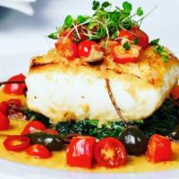 Halibut Mediterranean · Pan seared halibut in grape tomatoes, caper berries, olives over sautéed spinach.