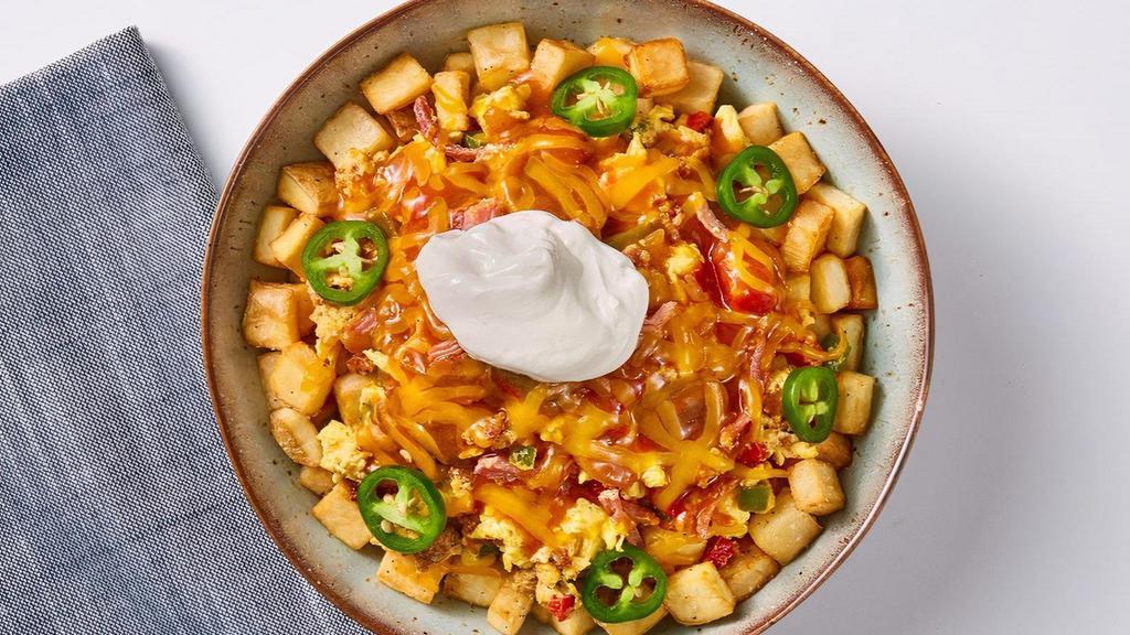 Southwestern Spicy Bowl · Let's spice it up! Seasoned country potatoes, topped with scrambled eggs mixed-in with sautéed diced red and green peppers, chorizo, and carnitas, topped with ranchero sauce and shredded cheddar cheese and finished with sour cream and jalapeno slices.