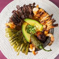 Molcajete · A molcajete filled with grilled skirt steak,chicken,shrimp,cactus,Mexican sausage, melted Oa...