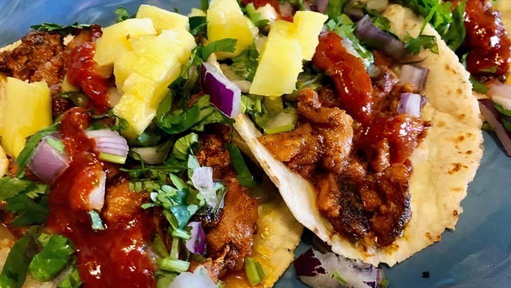 Al Pastor Taco · Pork marinated in chile and spice. . Topped with diced red onions, fresh cilantro, pineapple and our homemade red sauce.