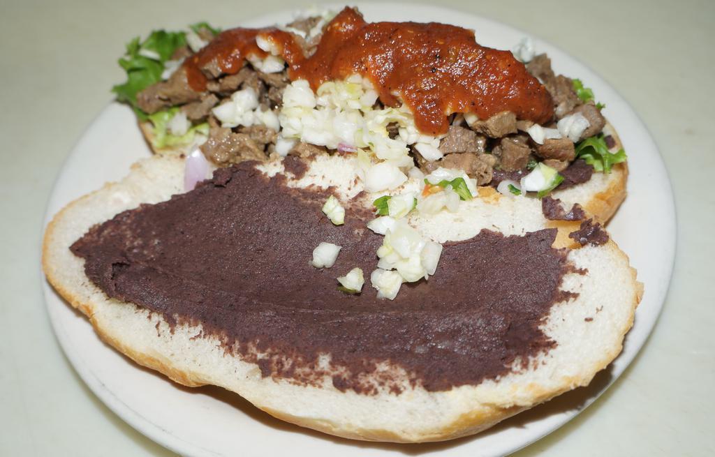 Carne Asada Torta · Beef, black beans, lettuce, red mild sauce and pico de gallo (cabbage, tomato, onion and cilantro). Served on a crusty white sandwich roll.