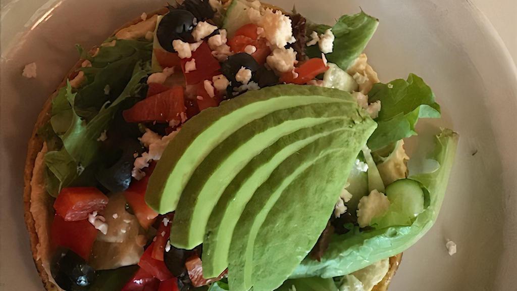 Hummus Tostada Gf (Add Falafel +$6) · (shown with added avocado) Crispy corn tortilla topped with homemade hummus, sun-dried tomatoes, greens, cucumbers, red peppers, black olives, and feta. Gluten-free. Vegan option. No feta, add avocado for additional cost.
