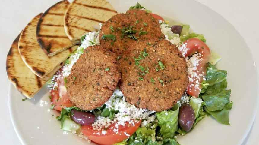 Falafel Plate · Four fresh-made falafels on a bed of hummus, topped with tahini, and chopped salad; served with pita bread.