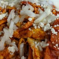 Chilaquiles Con Huevo · Crispy deep friend corn tortillas scrambled with eggs, and red sauce, topped with “ranchero”...