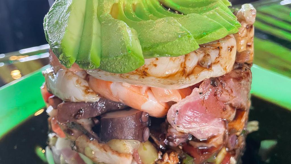 Torre De Mariscos · octopus, cooked shrimp, shrimp cooked in lime, scallops, aji tuna, salmon, shrimp and fish ceviche, red onion half moon cucumber topped with avocado and a black house sauce