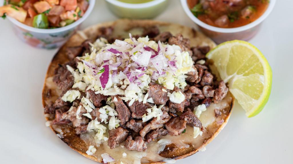 Steak Tostada · Crisp corn tortilla topped with melted Monterey Jack cheese, mesquite grilled carne asada, diced cabbage and diced red onion.