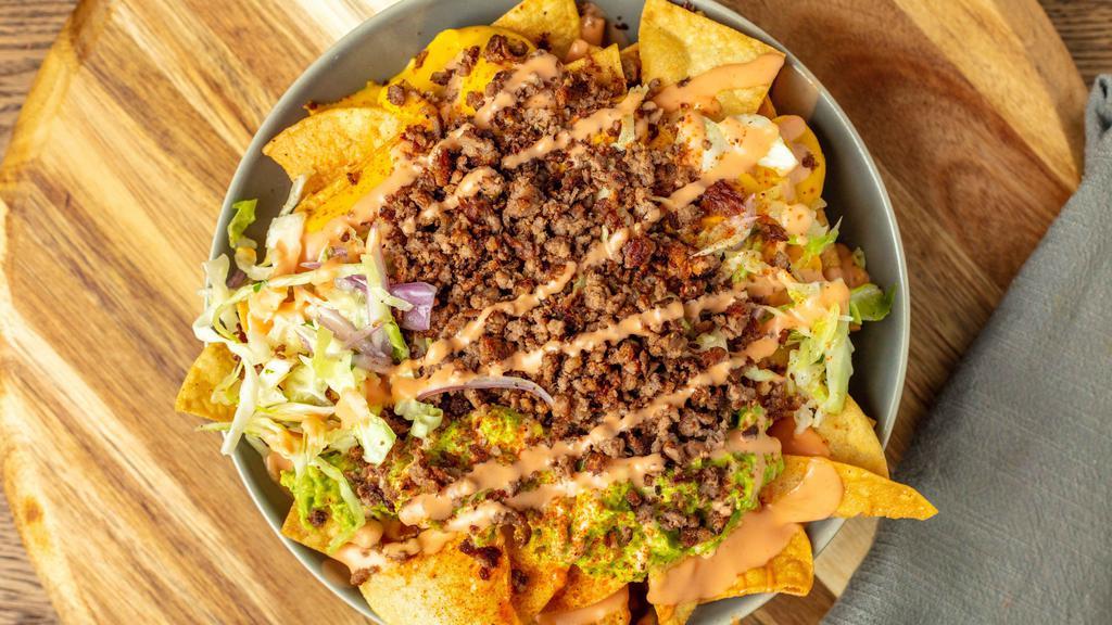 Solár Loaded Nachos · Large plate of nachos topped with Impossible Meat, house specialty coleslaw, guacamole aioli, cheese sauce, and Solár Sauce.
100% Plant-Based Vegan.