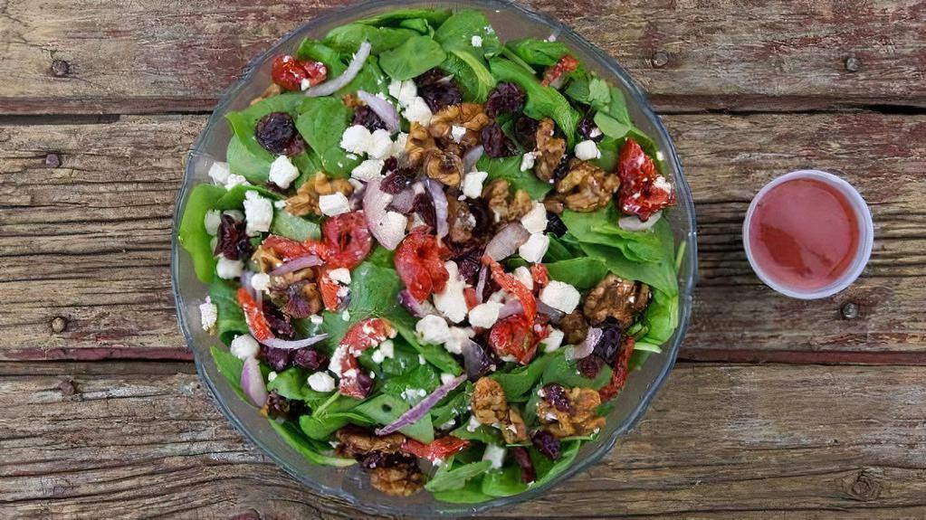 Spinach Salad · Fresh baby spinach, roasted red peppers, candied walnuts, choice of bleu cheese crumbles or feta cheese, red onions and dried cranberries and raspberry vinaigrette dressing.
