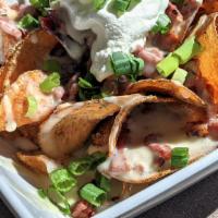 Irish Nachos · Homemade potato chips piled high & smothered with white cheddar sauce, corned beef, green on...