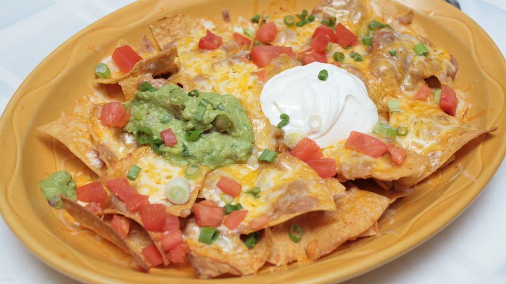 Vegetarian Super Nachos · Corn tortilla chips topped with whole beans, jalapeno poppers, green onions, and melted cheese chopped tomato. Served with guacamole, and sour cream.