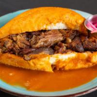 Torta Ahogada · Pork sandwich with beans purple onions and red sauce with another spicy sauce on the side se...