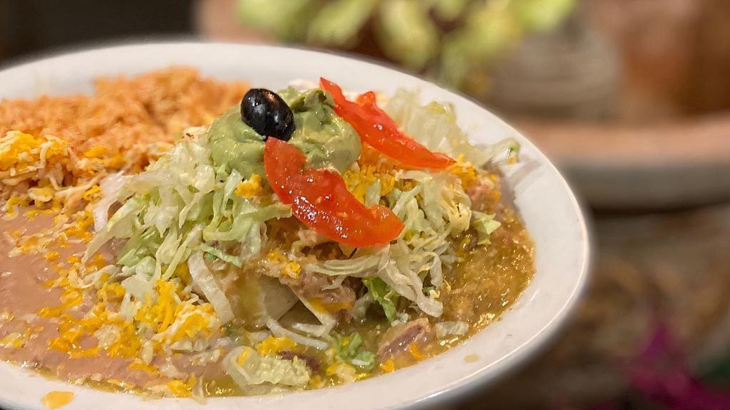 Smothered Burrito · Shredded beef burrito topped with pork chile verde, lettuce, cheese, sour cream, guacamole and tomatoes, and our own delicious green chile sauce. Served with Spanish rice and refried beans.