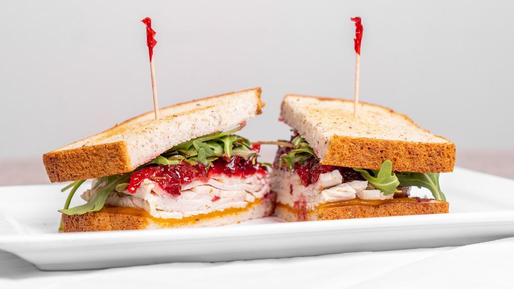 Turkey Cranberry Sandwich · Roasted turkey, cheddar cheese, arugula, house-made cranberry sauce on toasted gluten free multigrain bread. Served with choice of side.