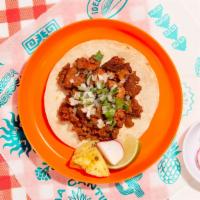 Al Pastor Taco · Spit roasted spicy pork with charred pineapple topped with cilantro and chopped onion on a s...