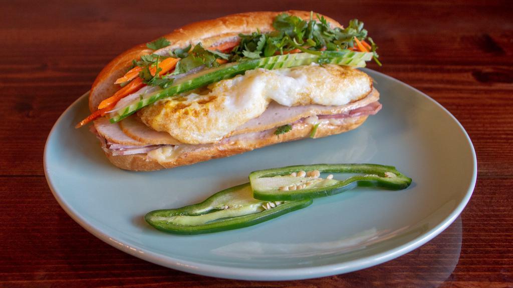 Xinhxinh Bánh Mì · French baguette with house-made mayonnaise, cucumber, pickled daikon-carrots, lean pork roll, Vietnamese ham, and headcheese with two eggs.